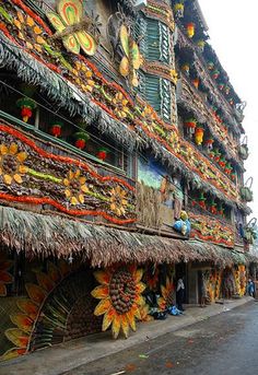 an elaborately decorated building on the side of a street with people walking down it