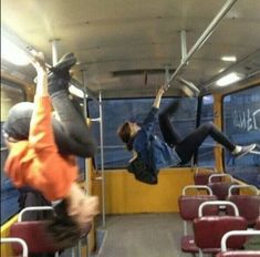 two people hanging upside down on a bus