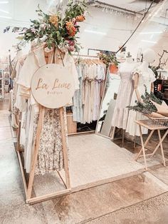 a clothing store with clothes on display and flowers hanging from the rack in front of it