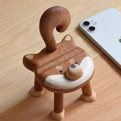 a wooden toy bear sitting on top of a table next to an iphone