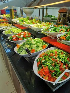 salads are lined up in bowls on the buffet line at a restaurant, ready to be eaten