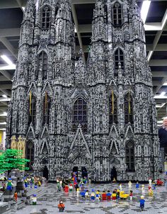 a large model of a cathedral made out of legos in a building with people looking at it