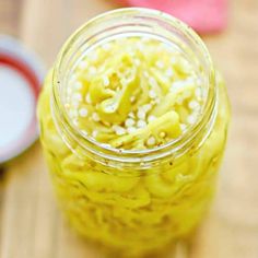 a jar filled with macaroni and cheese on top of a wooden table