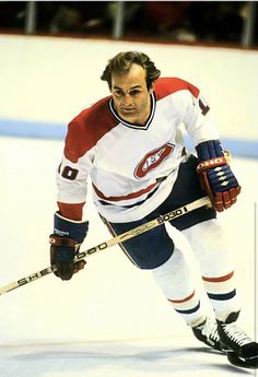 a hockey player is moving on the ice with his stick in hand and looking at the camera