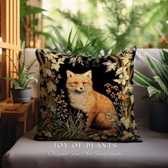 a pillow with a fox on it sitting next to a potted plant in front of a window