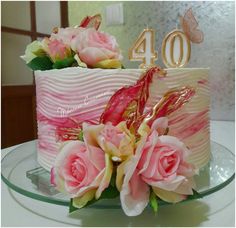 a pink and white cake with flowers on the top is sitting on a glass plate