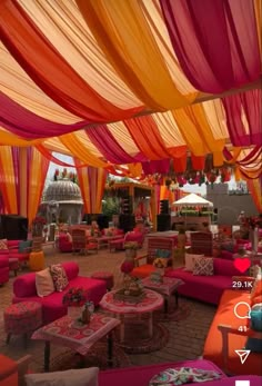 an outdoor seating area is decorated with bright colors and draping on the ceiling