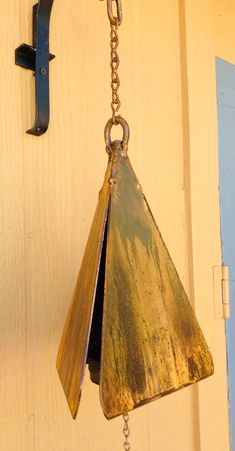 a metal bell hanging from a chain on a door