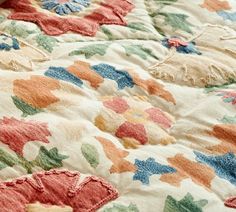 an image of a colorful quilt with flowers on the coverlet and pillows in the background