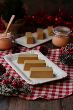 three pieces of cake sitting on top of a white plate next to two small jars