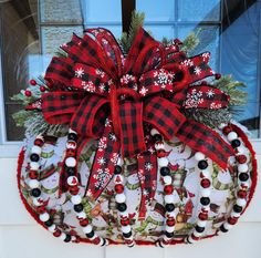 a red and black christmas wreath hanging on the front door