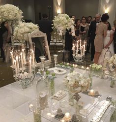 a group of people standing around a table with flowers and candles