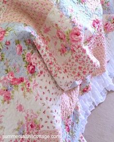 the bed is covered with pink and blue floral bedspreads, along with ruffled edges