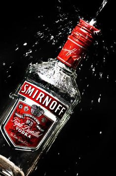 a bottle of smirnott vodka being dropped into the water by someone's hand