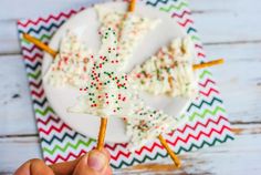 a person holding up a piece of cake on a stick with sprinkles