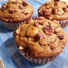 three muffins sitting on top of a blue plate with pecans in them