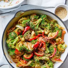 broccoli, peppers and onions in a skillet with sesame seeds on the side