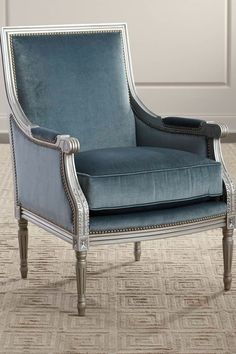 a blue chair sitting on top of a carpeted floor next to a white wall