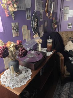 a room with purple walls and pictures on the wall, including flowers in vases