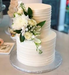 a wedding cake with white flowers and greenery