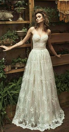 a woman standing in front of plants wearing a dress with flowers on the side and her arms out