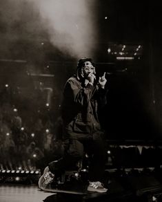 a man standing on top of a stage with his hand up in the air while holding a microphone