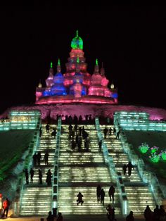 many people are walking up and down the stairs at night with colorful lights on them