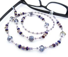 This eyeglass lanyard sparkles! Made with purple crystal glass, purple metallic glass seed beads, purple bugle beads and silver plated spacers. It is light weight which makes it very easy to wear. It measures about 29" in length from end to end and has stretchy eyeglass holders on the ends that will fit most any pair of glasses. It is strung on super strong Beadalon 49 strand wire with wire guardians for extra durability. YOUR CHOICE: (See 2nd Photo) Size: SMALL - 20mm or LARGE - 25mm (this is t Adjustable Purple Glass Beaded Necklaces, Adjustable Purple Glass Glasses Chains, Purple Metallic, Eyeglass Chain, Purple Crystal, Bugle Beads, Purple Crystals, Badge Holders Lanyard, Crystal Glass