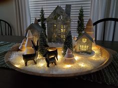 a wooden tray topped with christmas decorations and lights on top of a dining room table