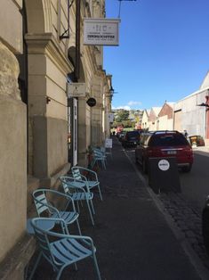 there are many blue chairs lined up on the side of the street next to each other