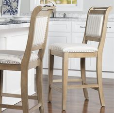 two wooden chairs sitting on top of a hard wood floor next to a kitchen counter