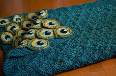 there is a crocheted blanket with peacocks on it