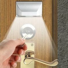 a person's hand is pressing the button on a door handle with a flashlight