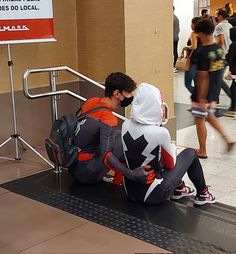 two people in costumes sitting on an escalator at the subway station, one wearing a mask