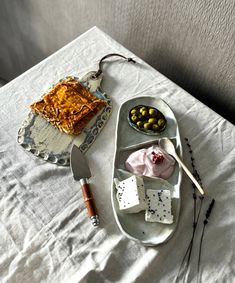 an assortment of food sitting on a tray next to a knife and fork, along with other items