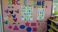 a pink bulletin board with mickey mouse numbers and shapes on it in a classroom setting