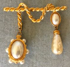 You are looking at a truly superb and absolutely exquisite VINTAGE VICTORIAN INSPIRED HUGE BAROQUE PEARLS ON SCULPTURAL ROPES RICH GILT GOLD-TONE METAL BROOCH PIN featuring TWO HUGE CHARMS IN THE SHAPE OF AN OVAL REVERSIBLE MEDALLION WITH A LARGE FAUX PEARL WITH SMALLER FAUX PEARLS ALL AROUND AND A LONG FAUX PEARL IN THE SHAPE OF A TEARDROP WITH AN OVAL FAUX PEARL ON TOP, done in an Avant-garde chic look, UNSIGNED, Circa 1980's. EXQUISITE AND SUPER RARE STATEMENT PIECE, IN PRISTINE AND IMMACULATE, NEVER WORN ABOVE EXCELLENT VINTAGE CONDITION AND LOOKING LIKE BRAND NEW THIS BROOCH IS JUST SPECTACULAR AND IS VERY REMINISCENT OF THE PEARL PIECES THAT KARL LAGERFELD PRODUCED IN THE 80's. Measurements: - Length: 2 7/8" (7,4 cm). - Width: 2 5/8" (6,7 cm). UNSIGNED VERY HIGH QUALITY PIECE. THIS B Elegant Clip-on Brooches For Formal Occasions, Elegant Baroque Brooches For Formal Occasions, Elegant Clip-on Brooches For Evening, Designer Runway, Vintage Victorian, Vintage Designer, Baroque Pearls, Gold Tone Metal, Karl Lagerfeld