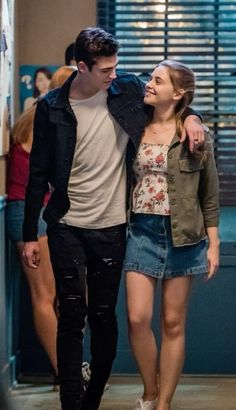 a young man and woman walking down a hallway