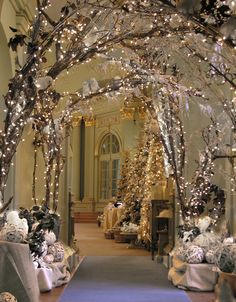 a hallway decorated for christmas with presents under the tree and lights on the trees in the background