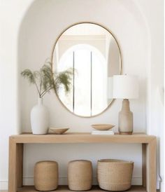 a mirror and some vases on a shelf in front of a table with a lamp