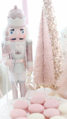 a nutcracker figurine next to pink macaroons