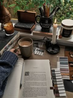 an open book sitting on top of a table next to a cup of coffee and other items