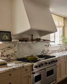 a kitchen with marble counter tops and stainless steel stove top oven, sink, and range hood