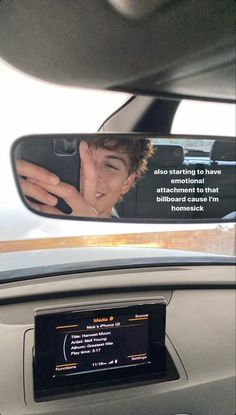 the rear view mirror is reflecting a young man's face