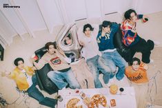 group of young people sitting on the floor with pizza and drinks in front of them