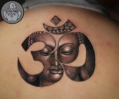 the back of a woman's shoulder with a tattoo design on it that has a buddha face