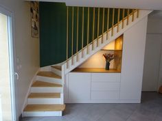 there is a vase with flowers sitting on the shelf under the stair case in this room