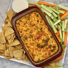 a casserole dish with carrots, celery and chips on the side