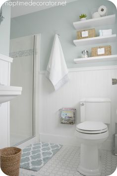 a white toilet sitting in a bathroom next to a sink and bathtub with shelves above it