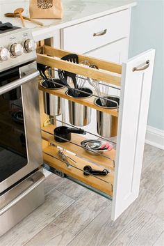 an oven with pots and pans in it next to a counter top drawer that holds utensils